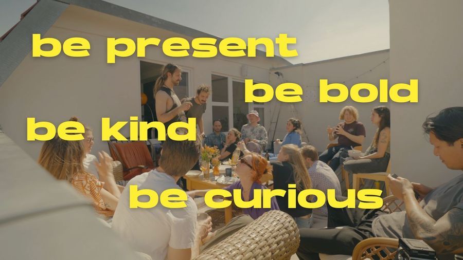 A rooftop gathering in Berlin with the words be present, be bold, be kind, be curious written over it